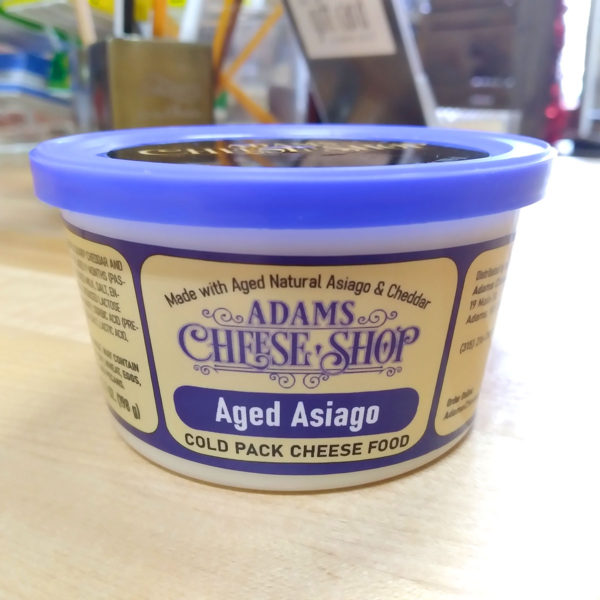 A tub of Aged Asiago cheese spread.