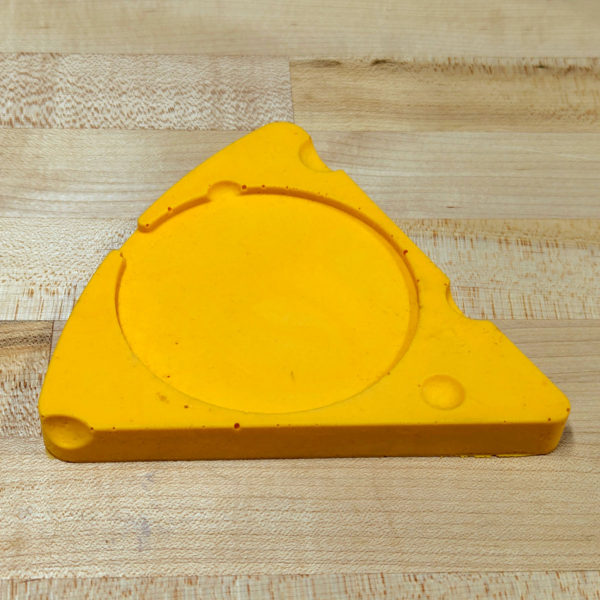 A cheese wedge shaped drink coaster, made of polyurethane foam.