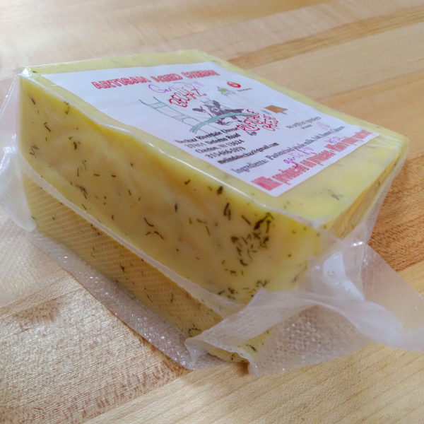 Closeup of a wedge of Garlic Dill aged artisan cheese.