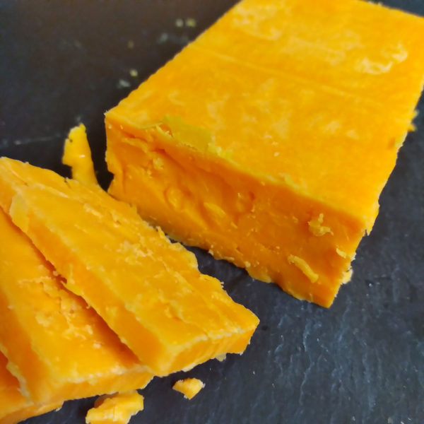 A cut up block of Red Fox Aged Red Leicester cheese.