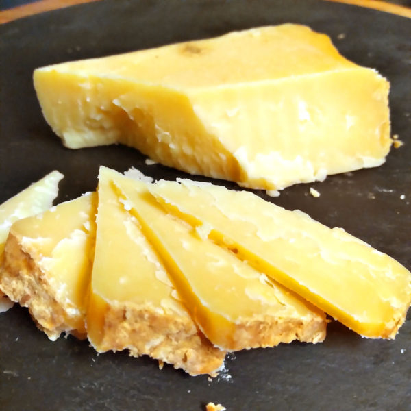 A cut up block of Jasper Hill Cave Aged Cheddar cheese.