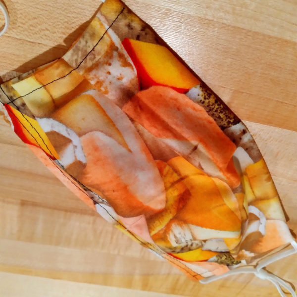 Closeup view of PPE face mask with cheese-patterned fabric.