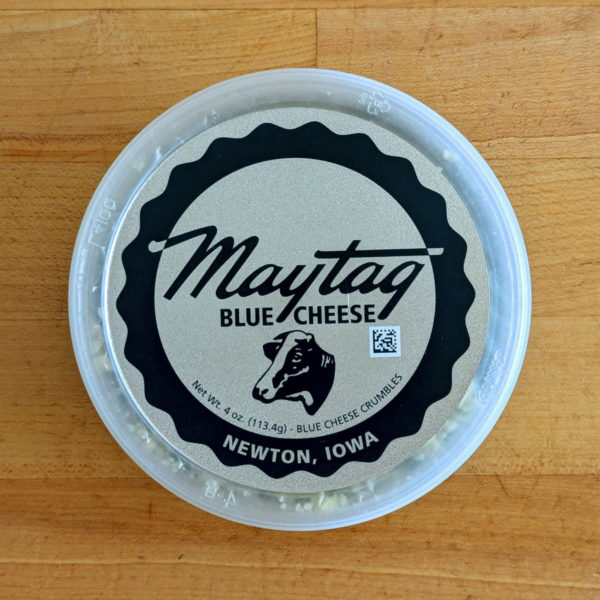 The lid of a container of Maytag Blue Cheese crumbles, displaying the logo.