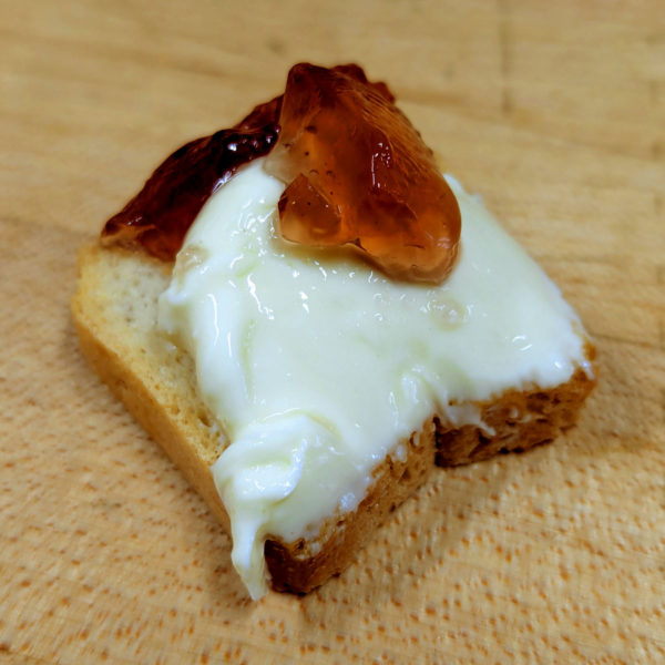 Just for Cheese Raspberry Rose Sichuan Pepper spread onto brie on top of a cracker.