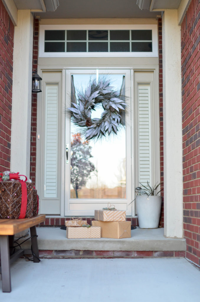 Four brown gift boxes near a glass paneled door with wreath.