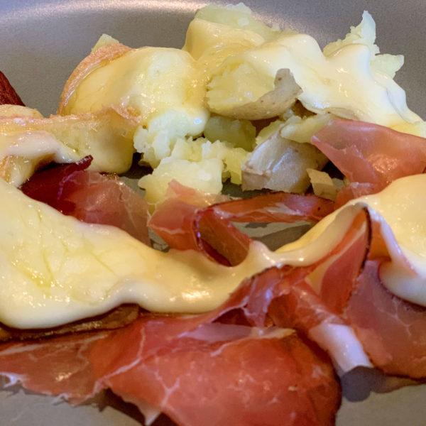 Raclette cheese melted over potatoes and sliced, cured meat.