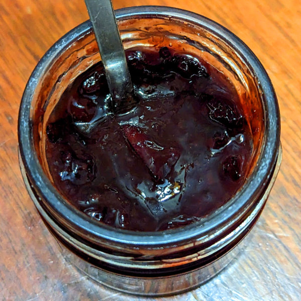 An open jar of black grape and almond Just for Cheese pairing.