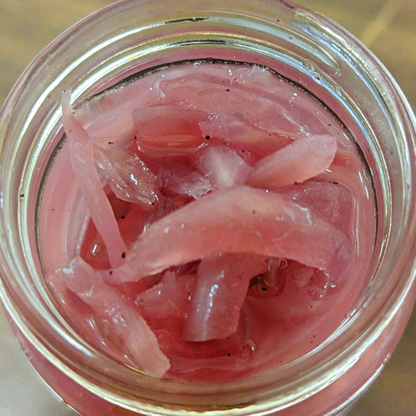 An open jar of sliced red onions.