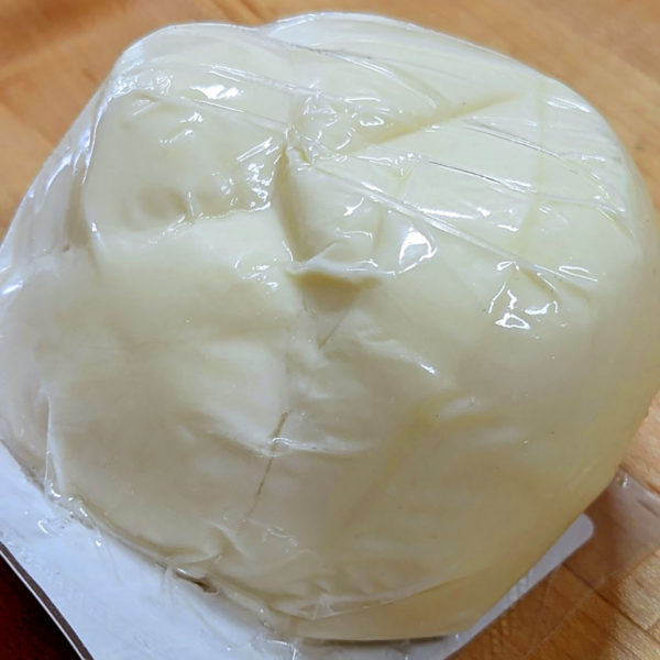 A closeup view of a ball of Oaxaca cheese in the packaging.