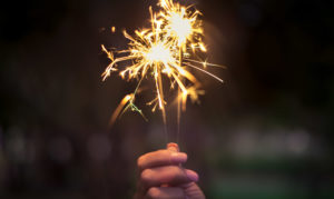 Person holding lighted sparkler.