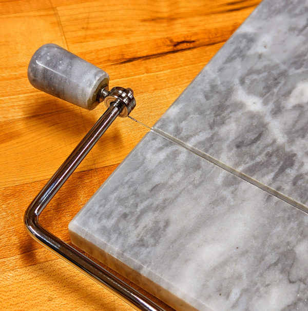 A closeup of the handle and cutting wire on the White Marble Cheese Slicer.