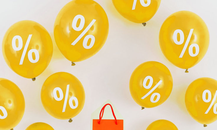 An orange paper bag in the middle of yellow ballons with percentage symbols.