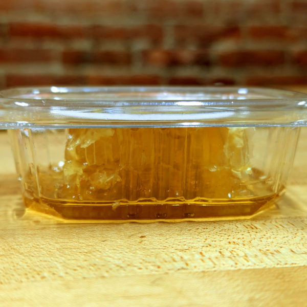 Side view of a container of cut honey comb.