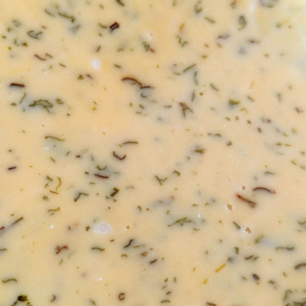 An extreme closeup of Green Goddess Gouda, speckled with green herbs.