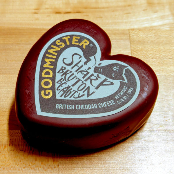 A closeup view of a heart-shaped Sharp Bruton Beauty cheese in burgundy wax.