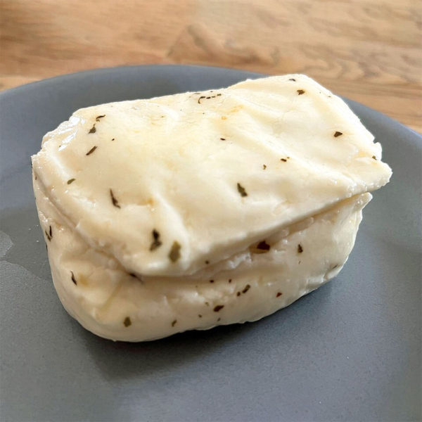 A small block of seasoned halloumi cheese, unwrapped and on a plate.