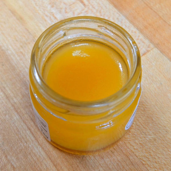 A closeup of an open jar of lemon curd.