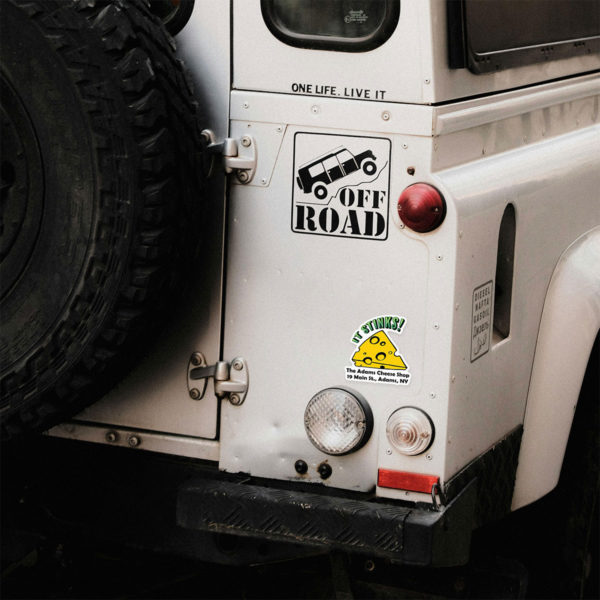 The "It Stinks!" magnet on the rear of a large off-road vehicle.
