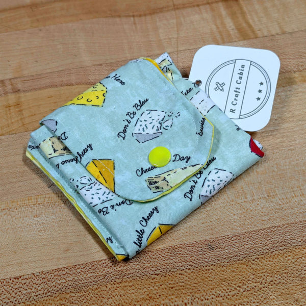 A cloth credit card, holder, closed, made from fabric with a cheesy pattern.