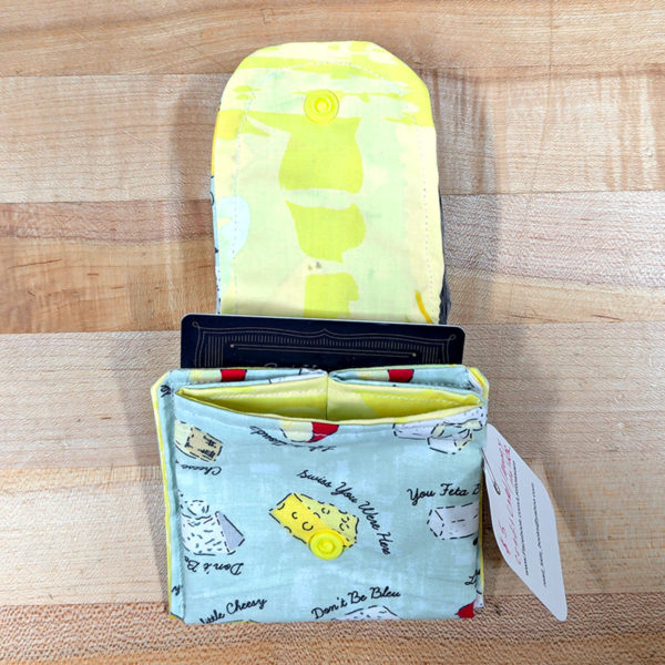 A cloth credit card, holder, open and with a card inside, made from fabric with a cheesy pattern.