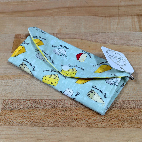 A glasses case, closed, made from fabric with a cheesy pattern.