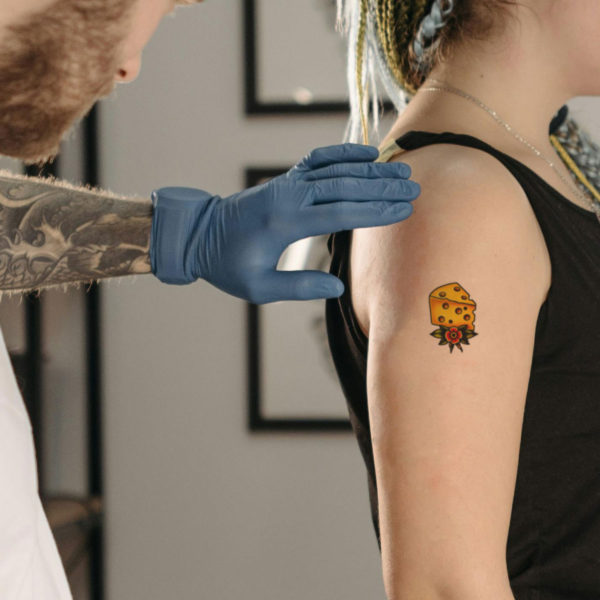 A tattoo artist looking over the cheesy temporary tattoo on a client's arm.