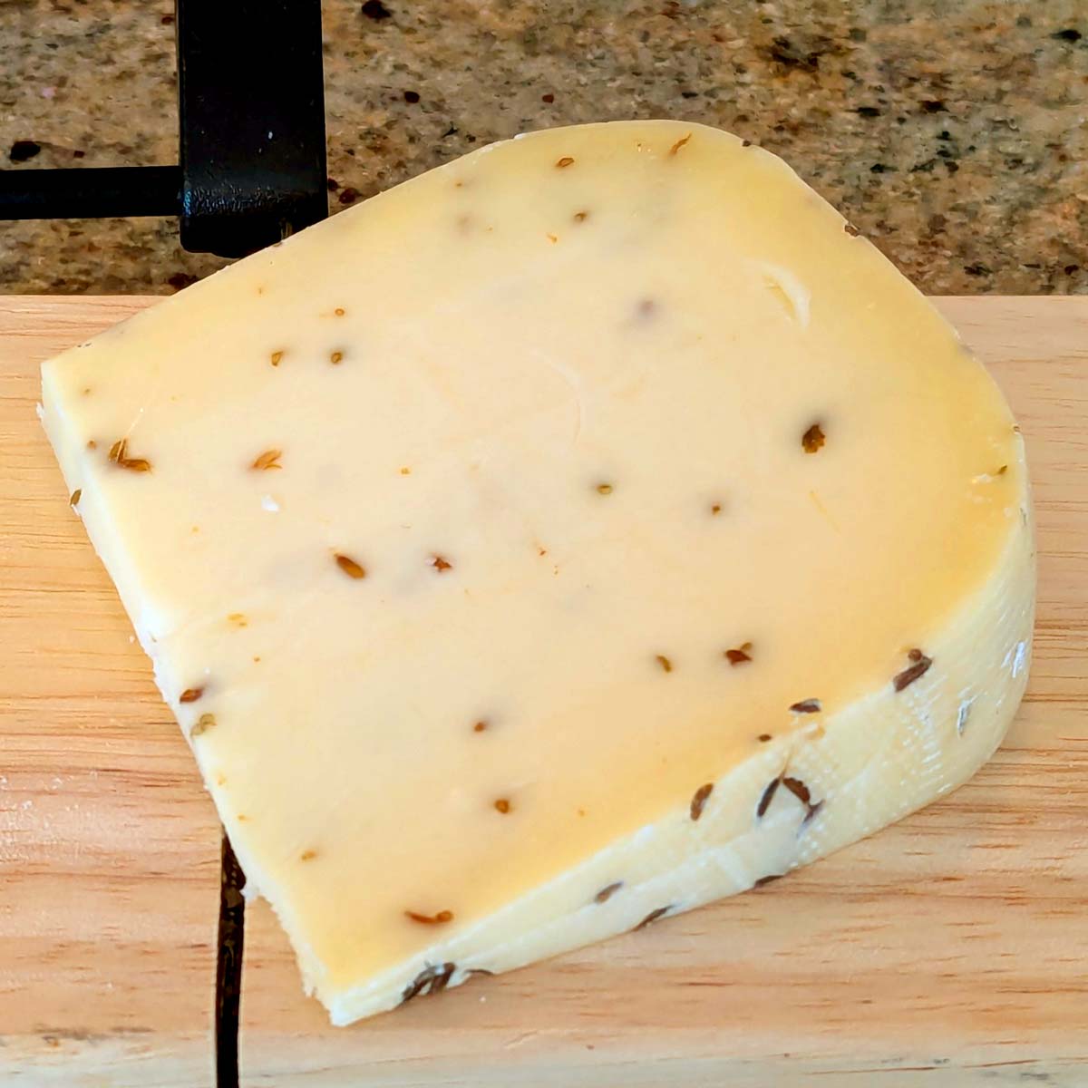 An unwrapped wedge of Gitane on Weck on a cutting board.