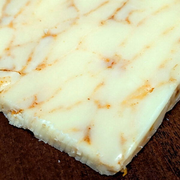 Closeup of an unwrapped wedge of Mafia Cheddar.