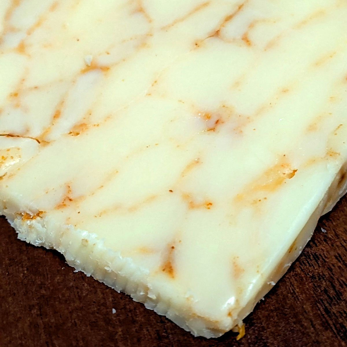 Closeup of an unwrapped wedge of Mafia Cheddar.
