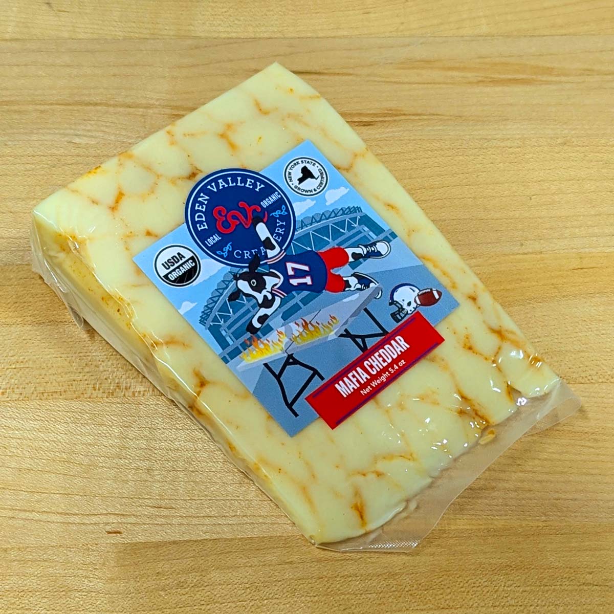 An angled view of a wedge of Mafia Cheddar, in the wrapper.