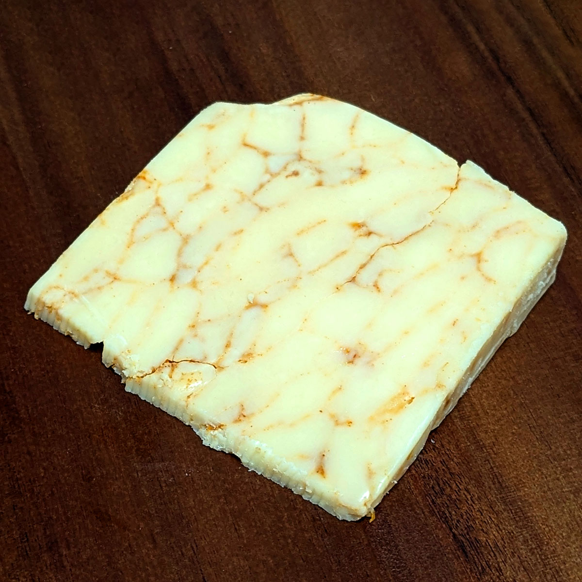 An unwrapped wedge of Mafia Cheddar.