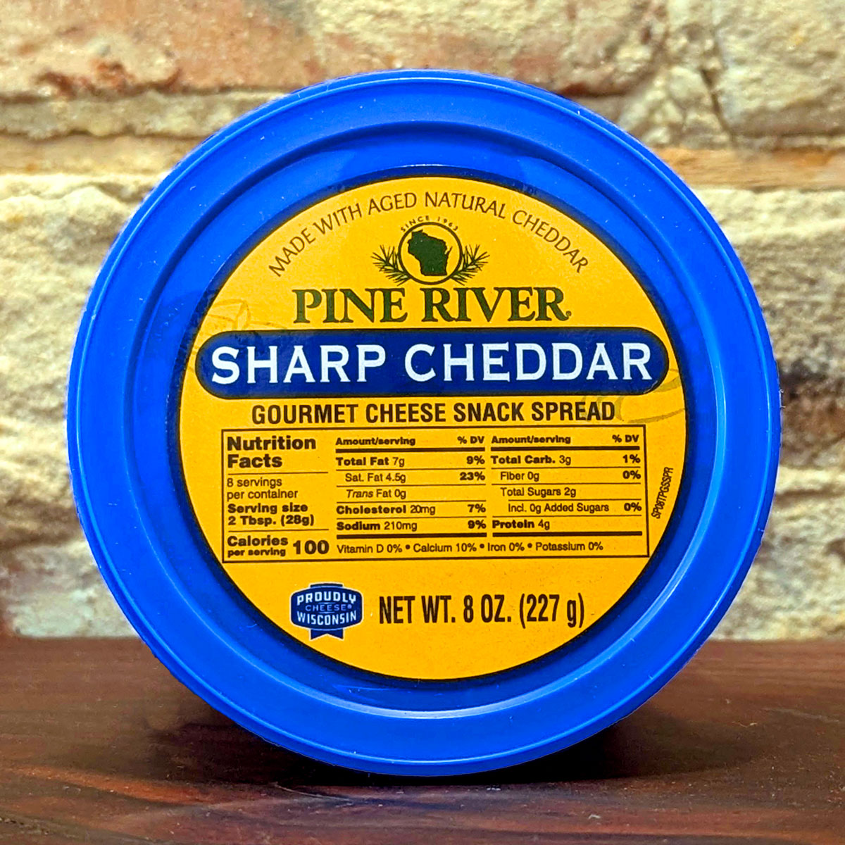 A top-down view of the lid and label for Sharp Cheddar gourmet cheese spread.